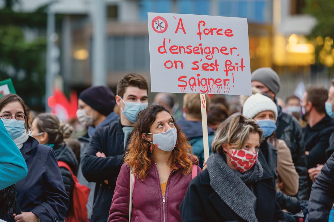 Une femme tient un panneau "à force d'enseigner, on s'est fait saigner' lors de la Manifestation de la fonction publique, Genève, 29 octobre 2020.