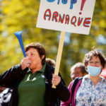 Une employée de la Ville de Genève tient une pancarte "Stop arnaque"
