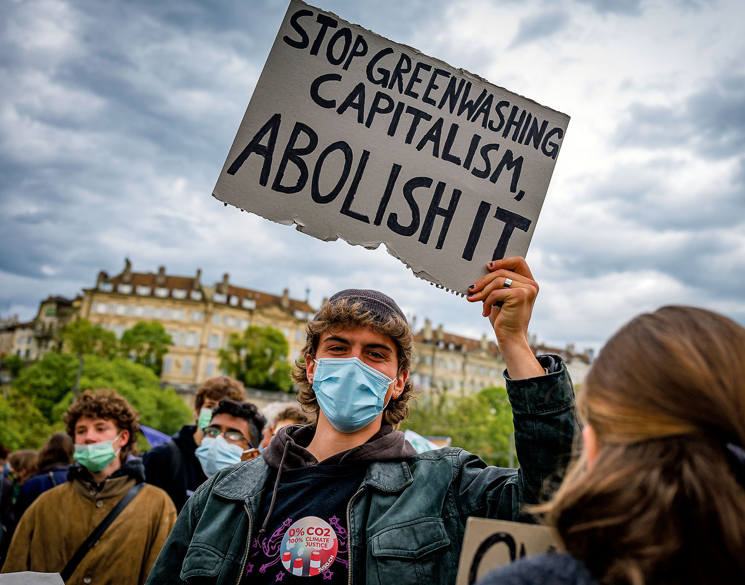 Un manifestant tient une banderole "Stop Greenwashing capitalism, abolish it”
