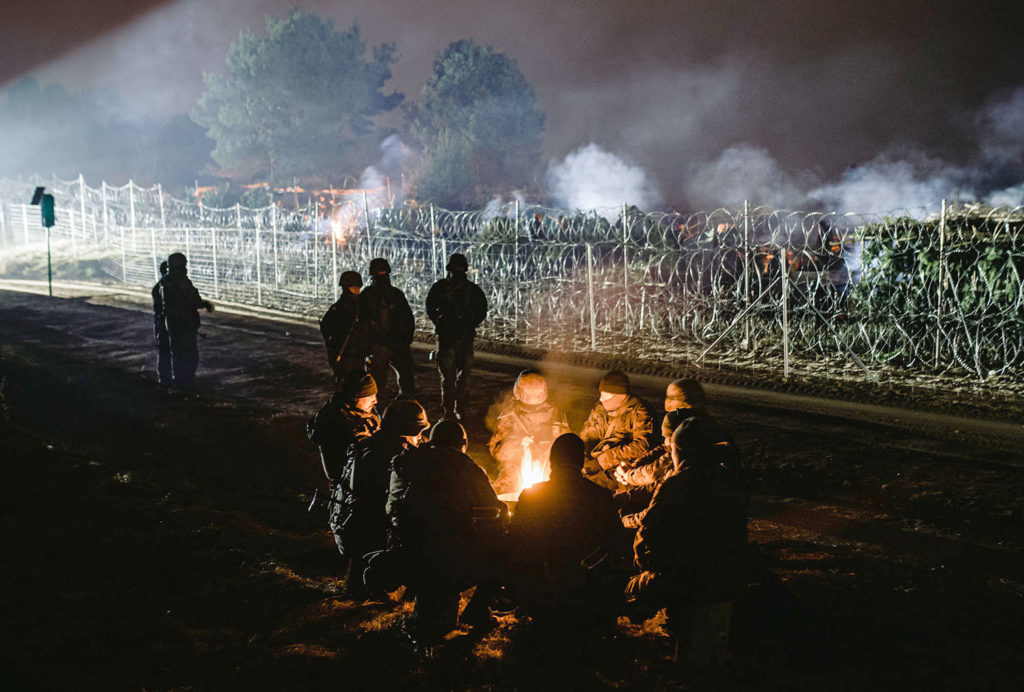 Des migrants autour d’un feu dans la nuit à la frontière entre la Pologne et la Biélorussie