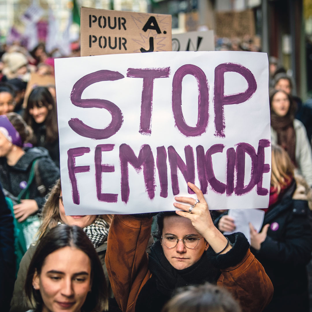 Une manifestante tient une pancarte "stop féminicide"
