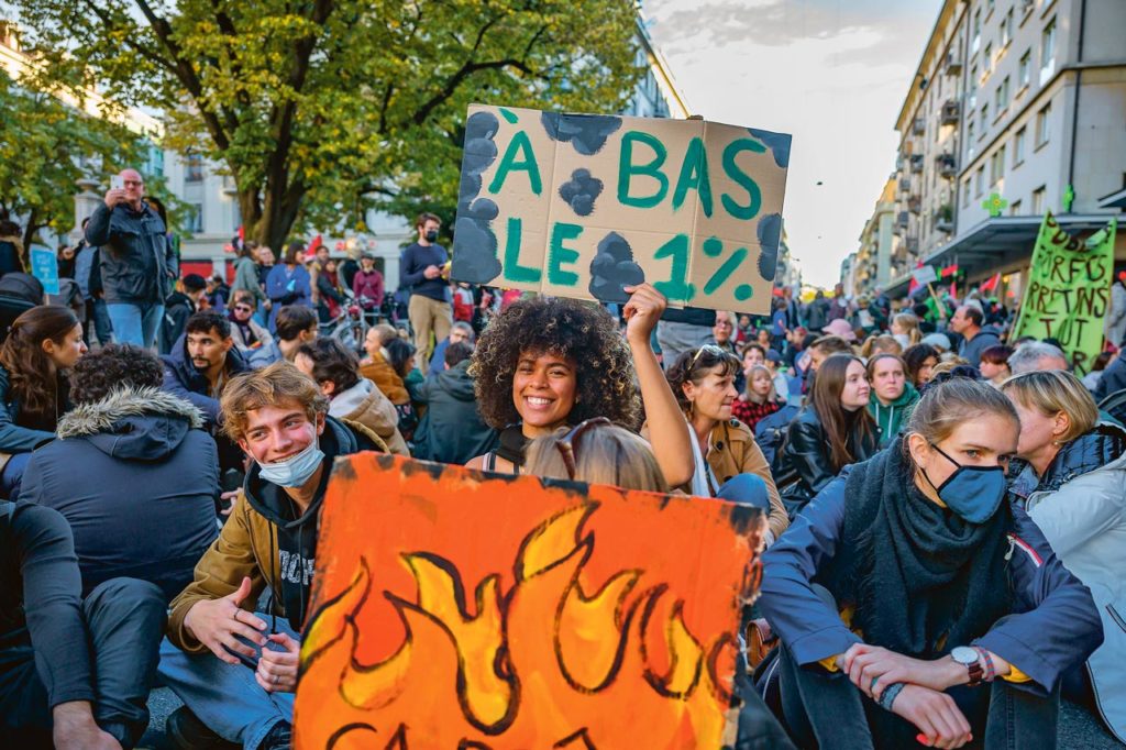 Une manifestante tient une banderole 'à bas le 1%' lors de la manifestation 'la planète brûle on attend quoi?^