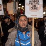 Une femme Rrom tient une pancarte "mendier n'est pas un crime"