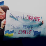 Une femme porte une pancarte "Support Ukraine! Save peace in Europe"