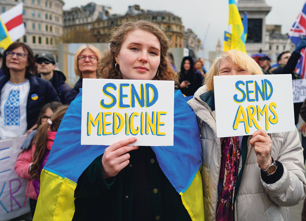 Deux manifestantes contre la guerre en Ukraine tiennent des pancartes "send medicine" et "send arms"