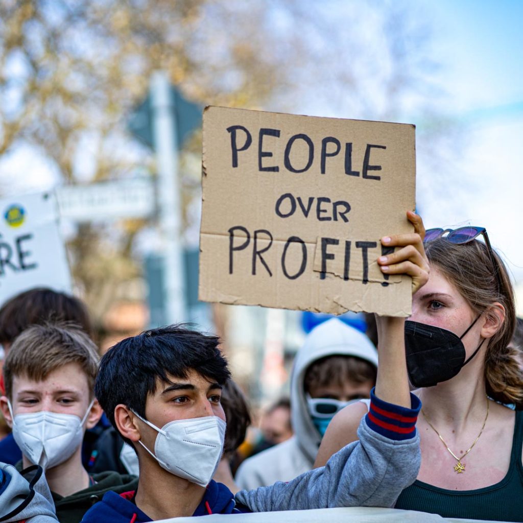 Un manifestant tient une banderole People over profit