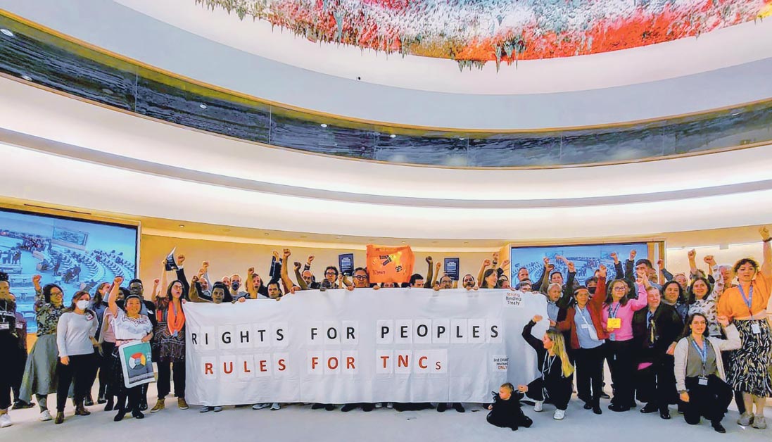 Un groupe de personnes déploie une banderole pour les droits des peuples contre les multinationales à l’ONU à Genève