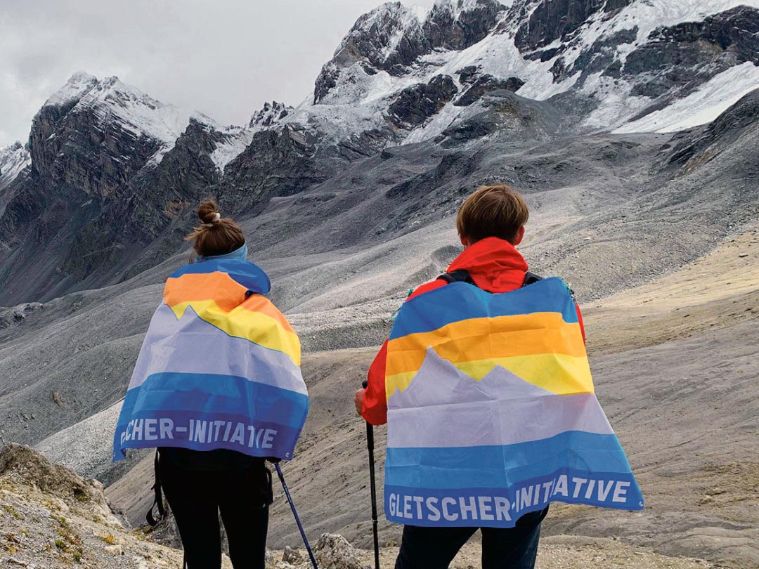 Deux femmes marchent en montagne avec des drapeaux de l'initiative des glaciers