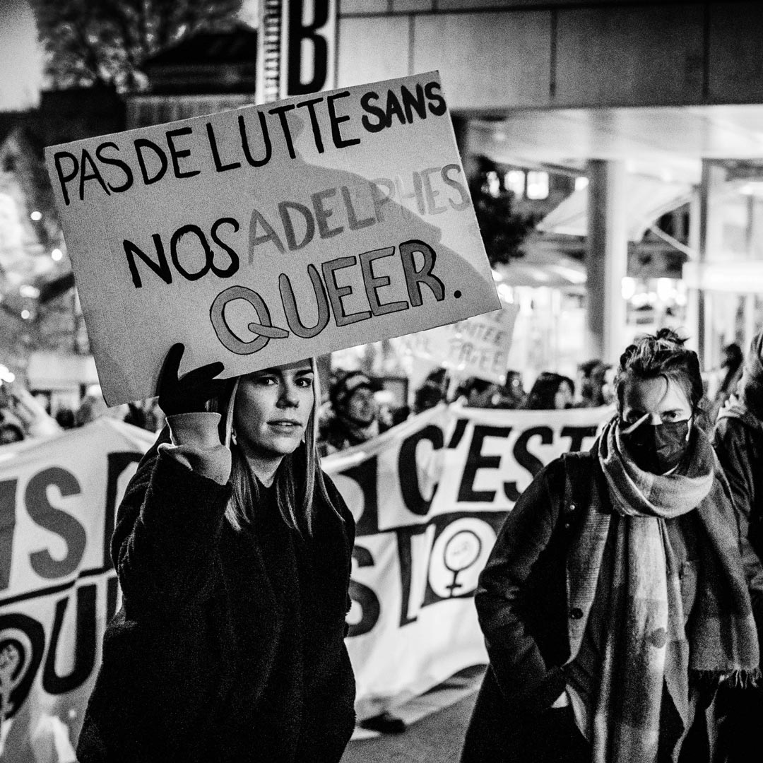 Une manifestante lors du cortège de la Journée des droits des femmes à Lausanne tient une pancarte "Pas de lutte sans nos adelphes queer"