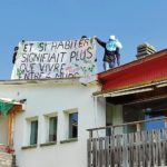 Des occupants du quartier libre de Clendy-Dessous tiennent une banderole "Et si habiter signifiait plus que vivre entre 4 murs?"