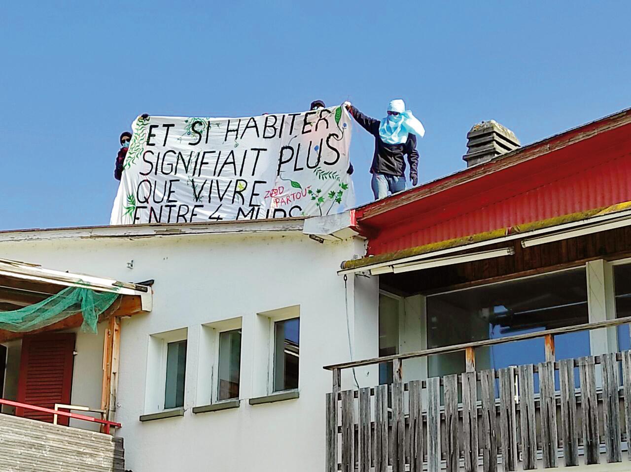 Des occupants du quartier libre de Clendy-Dessous tiennent une banderole "Et si habiter signifiait plus que vivre entre 4 murs?"