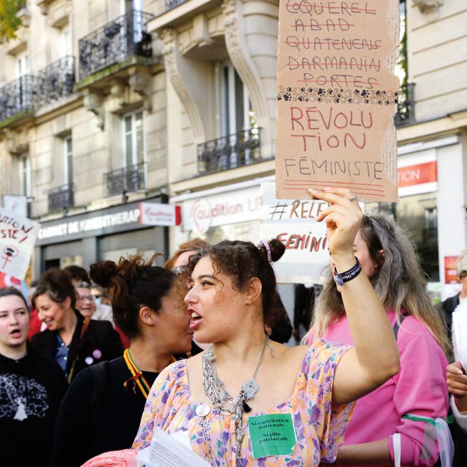 Une manifestante porte une pancarte avec le nom de politiciens français accusés de violences sexistes