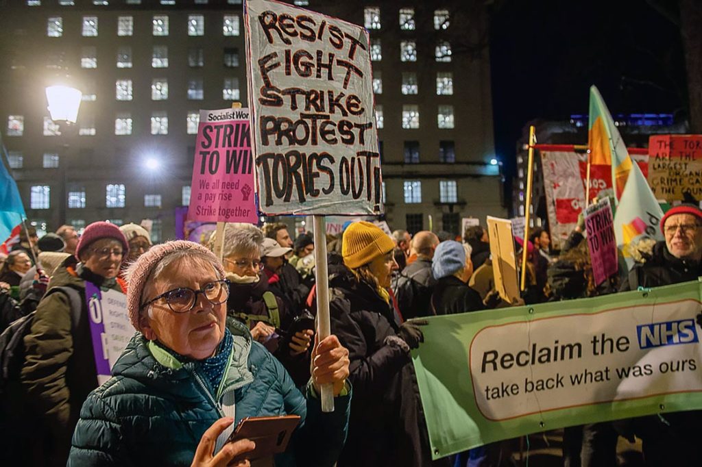 Une manifestante tient une banderole «Resist, Fight, Strike, Protest, Tories out!»