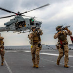 Trois soldats armés sur un porte-avion en mer des Philippines