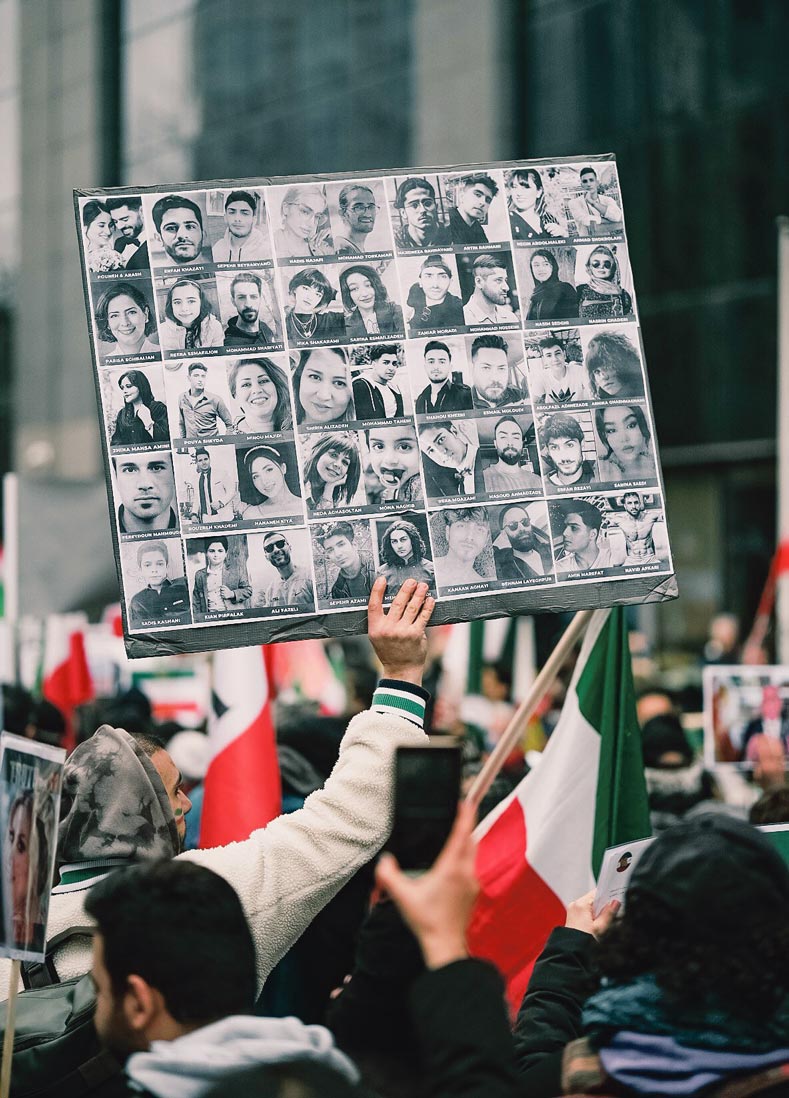 Une manifestante tient une pancarte avec des photos de victimes du régime iranien