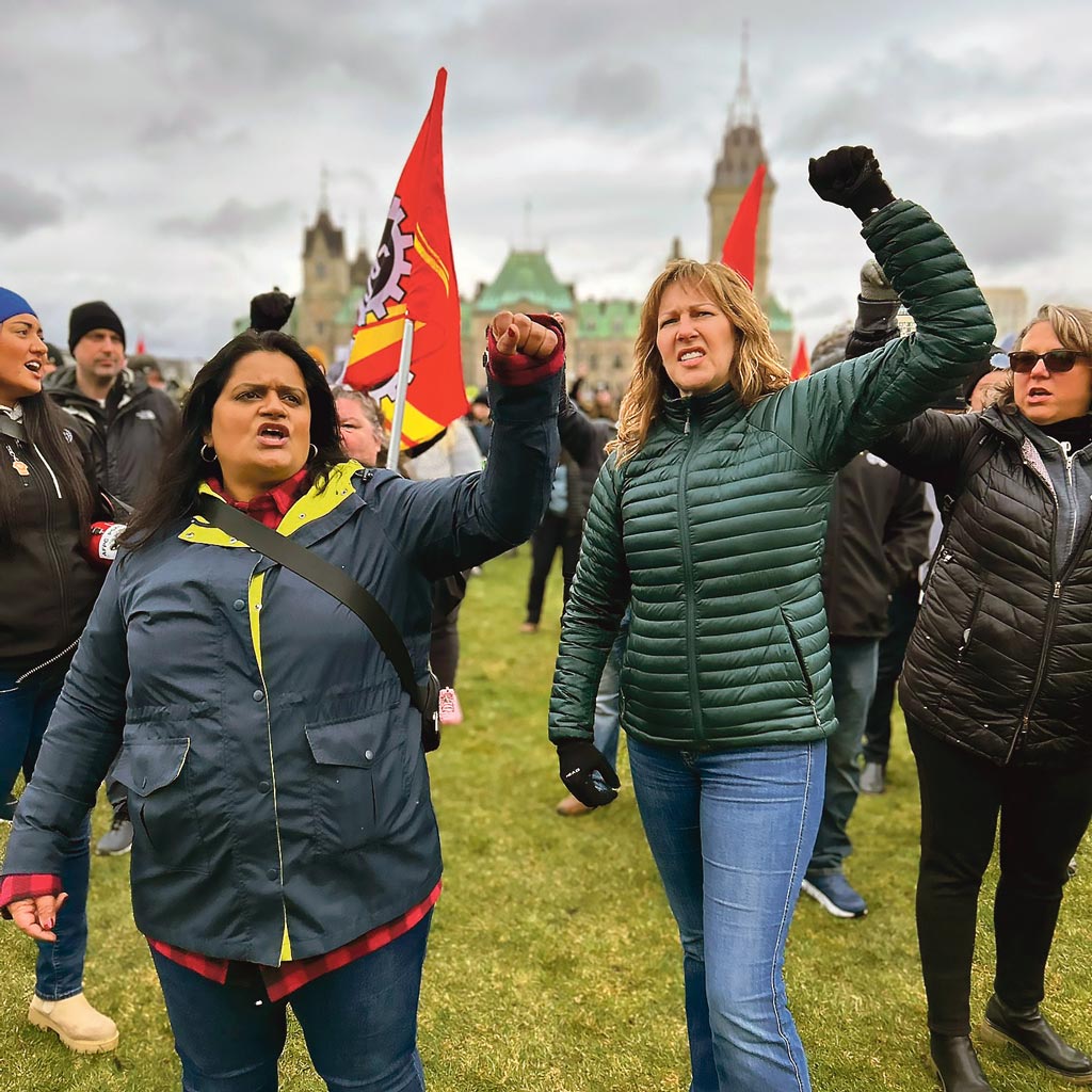 Deux grévistes brandissent le poing devant le parlement d’Ottawa