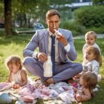 Un père en costume cravate avec ses 4 enfants dans un parc