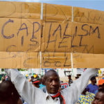 Un manifestant nigérian tient une pancarte contre le capitalisme