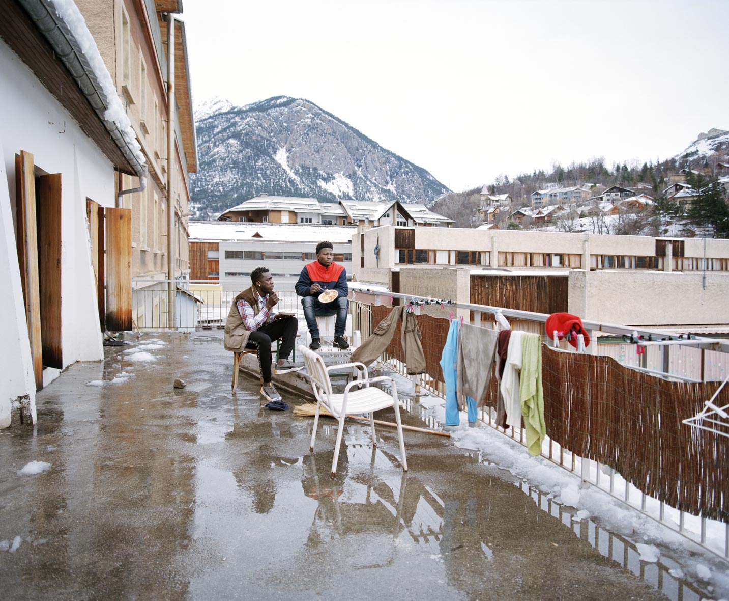 Deux migrants sur la terrasse du refuge solidaire de Briançon. Photo de l'expo de Elisa Larvego