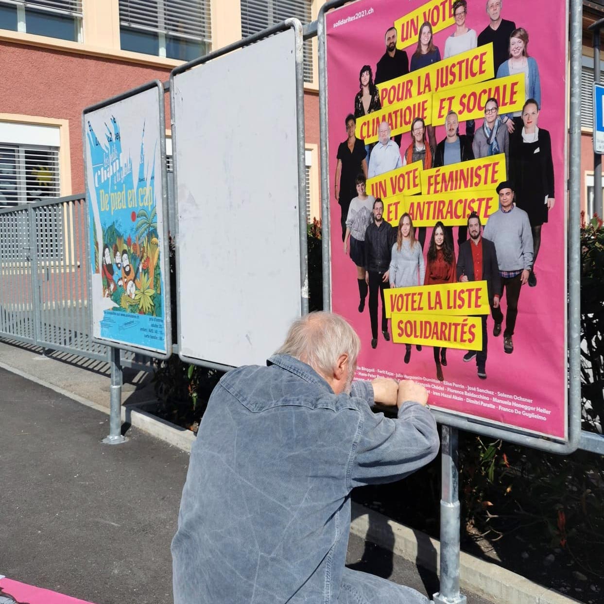 Un militant colle une affiche de solidaritéS lors des élections cantonales neuchâteloises 2021