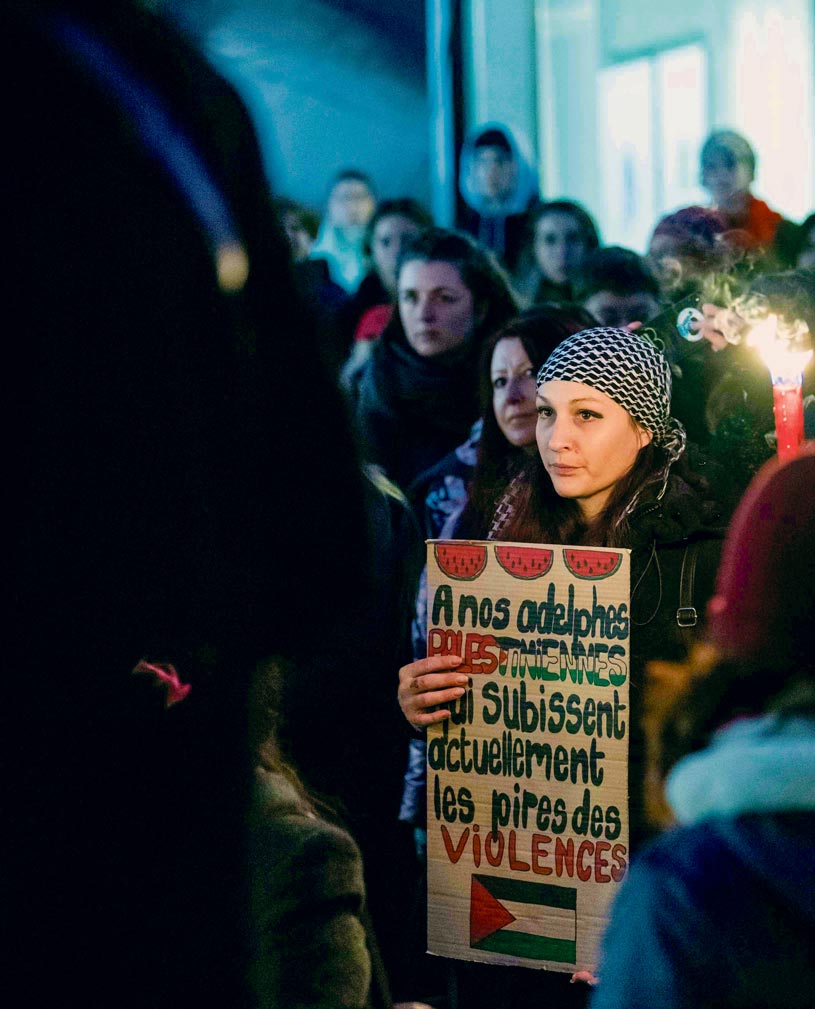 Une manifestante contre les violences sexuelles tient une pancarte en solidarité avec la Palestine