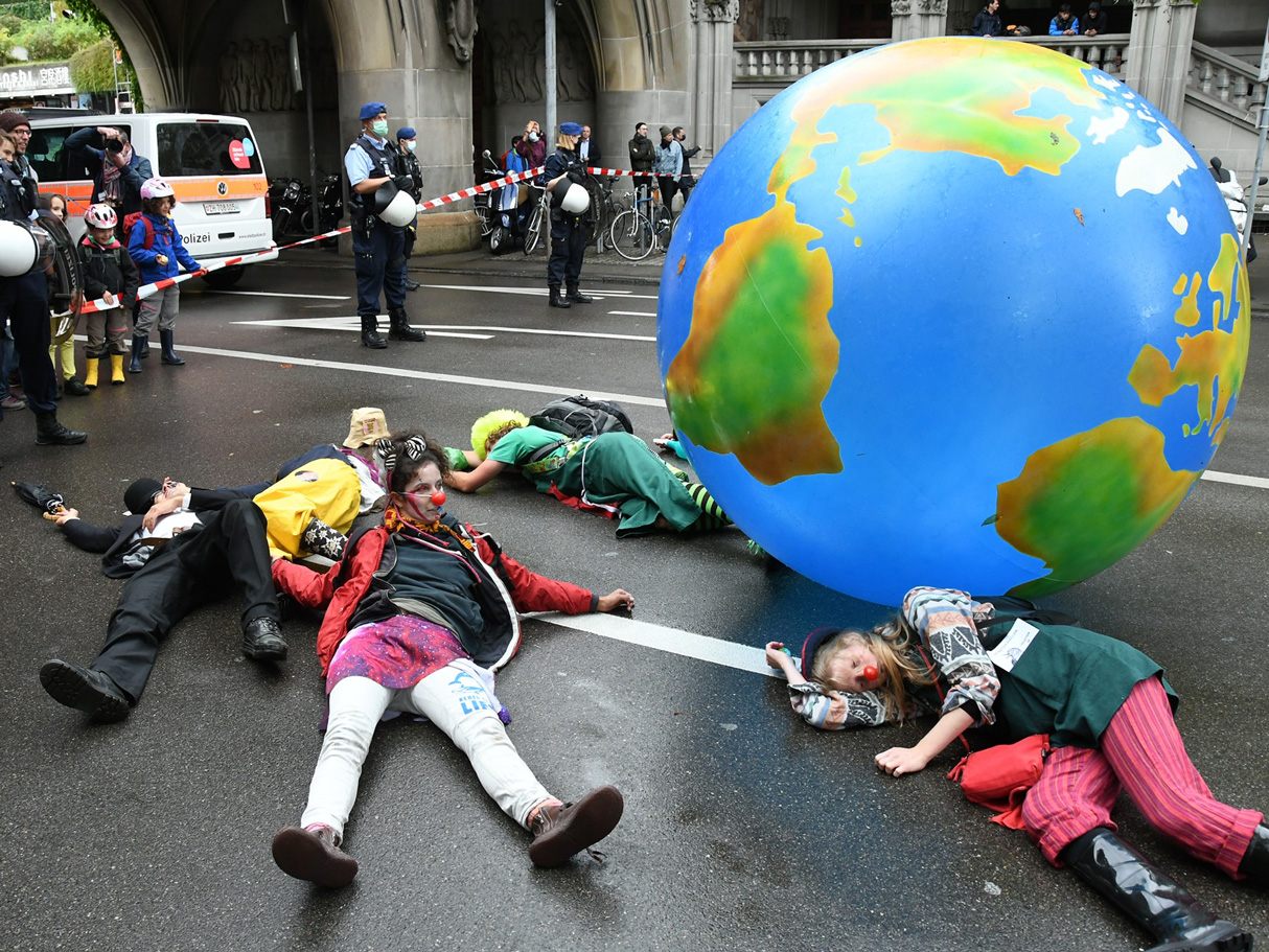 Des manifestants pour le climat couchés sur la route à côté d’une planète gonflable
