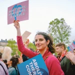 Une manifestante conte la transphobie tient une pancarte "mon corps, mon genre, ta gueule”