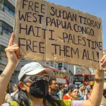 Une manifestante tient une pancarte "Free Sudan, Tigray, West Papua, Congo, Haiti, Palestine. Free them all” lors d'une marche pour le Soudan