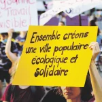 Une manifestante tient une pancarte "ensemble créons une ville populaire, écologique et solidaire"