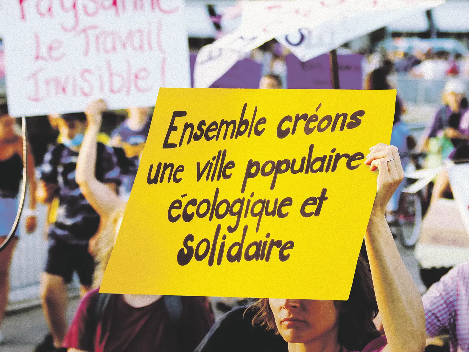 Une manifestante tient une pancarte "ensemble créons une ville populaire, écologique et solidaire"