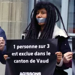 Une personne bâillonnées tient une pancarte "1 personne sur 3 est exclue dans le canton de Vaud", pour réclamer l'extension du droit de vote des étrangers