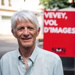 Portrait d'Yves Christen devant une affiche contre les caméras de surveillance à Vevey