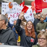 Une manifestante lève un carton rouge contre le plan d'économies du Canton de Fribourg