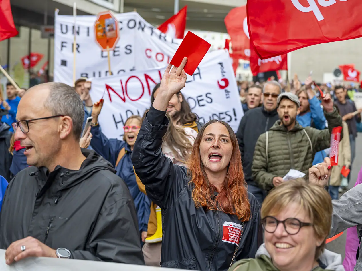 Une manifestante lève un carton rouge contre le plan d'économies du Canton de Fribourg