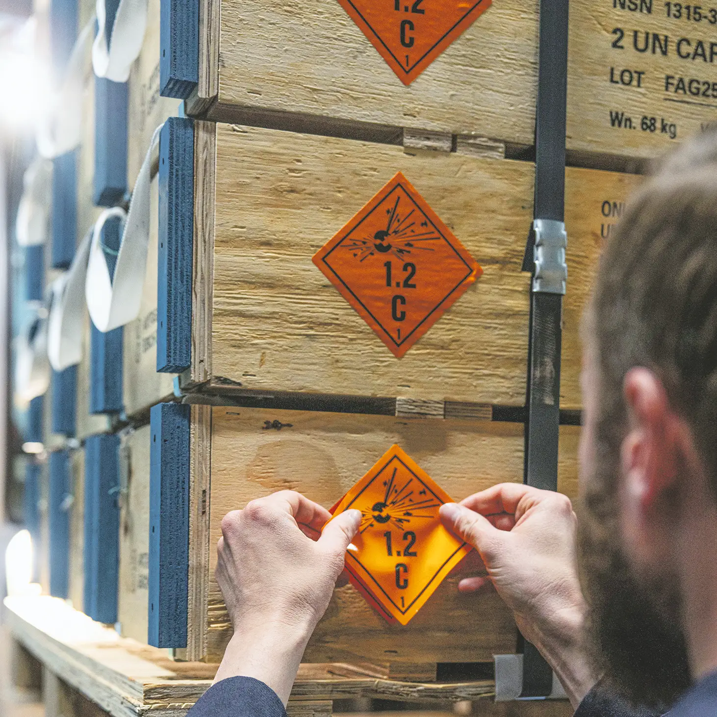 Un ouvrier colle un étiquette danger sur une caisse de munitions