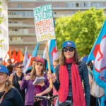 Pancarte “frontières ouvertes, magasins fermés le dimanche”, lors du cortège du 1er Mai 2026, Genève