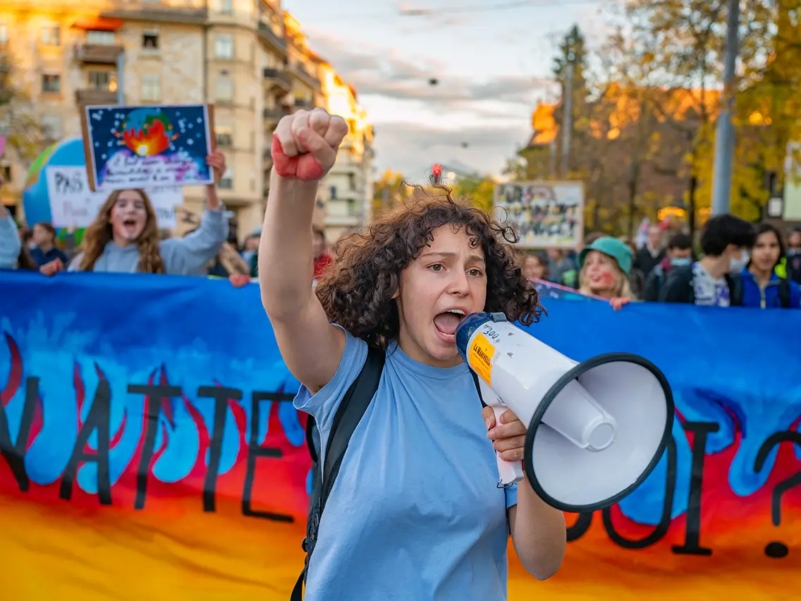 Une manifestante pour le climat devant une banderole avec des flammes