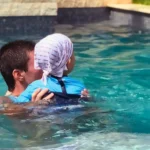 Un enfant avec portant des vêtements anti-UV dans une piscine