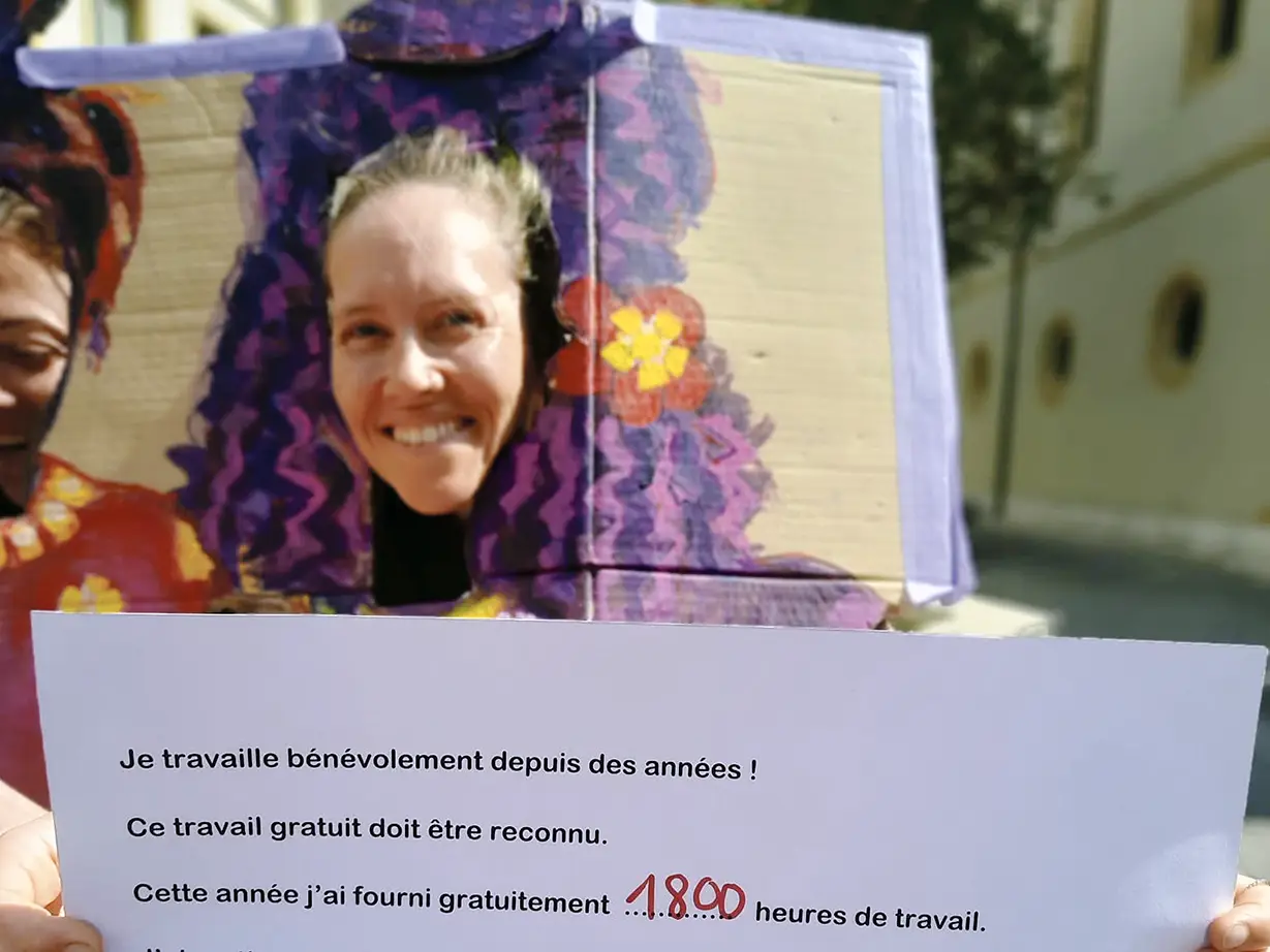 Une jeune femme tient une pancarte à propos du travail domestique